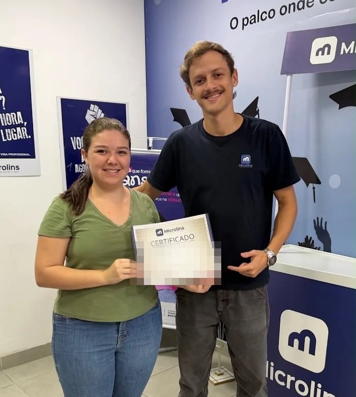 Aluna recebendo certificado de conclusão de curso ao lado de instrutor da Microlins Nova Friburgo