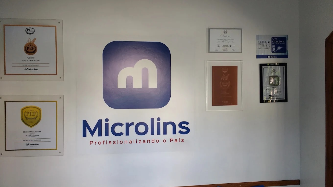 Parede de prêmios da Microlins Nova Friburgo, com premiações PEF e selo de Excelência em Franchising da ABF